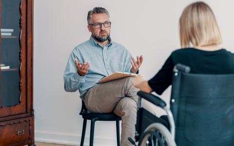 Berater im Gespräch mit Frau im Rollstuhl
